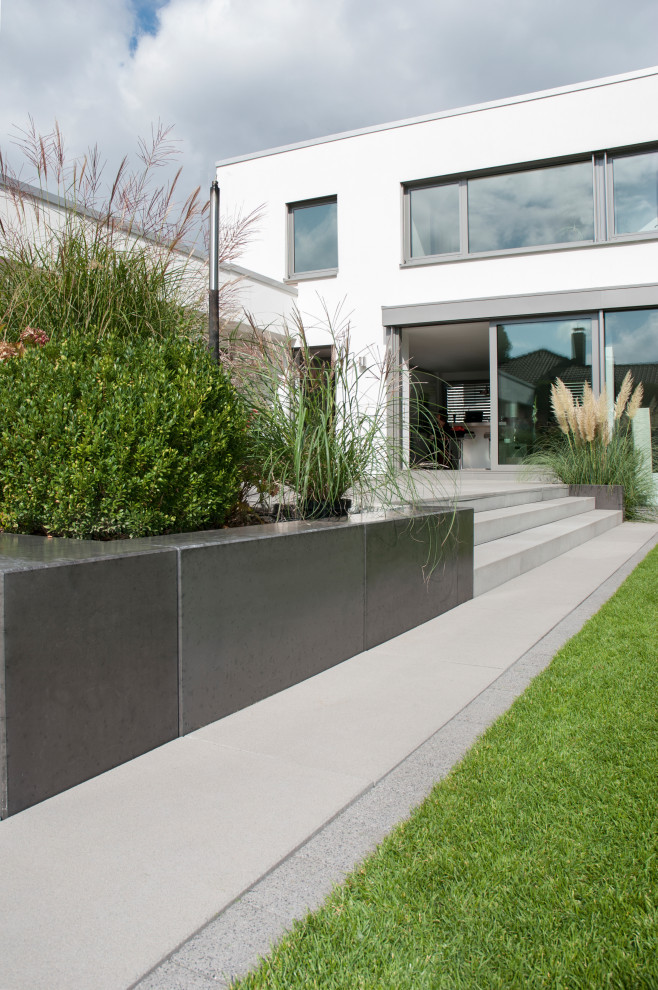 Photo of a contemporary front garden with a pathway and concrete paving.