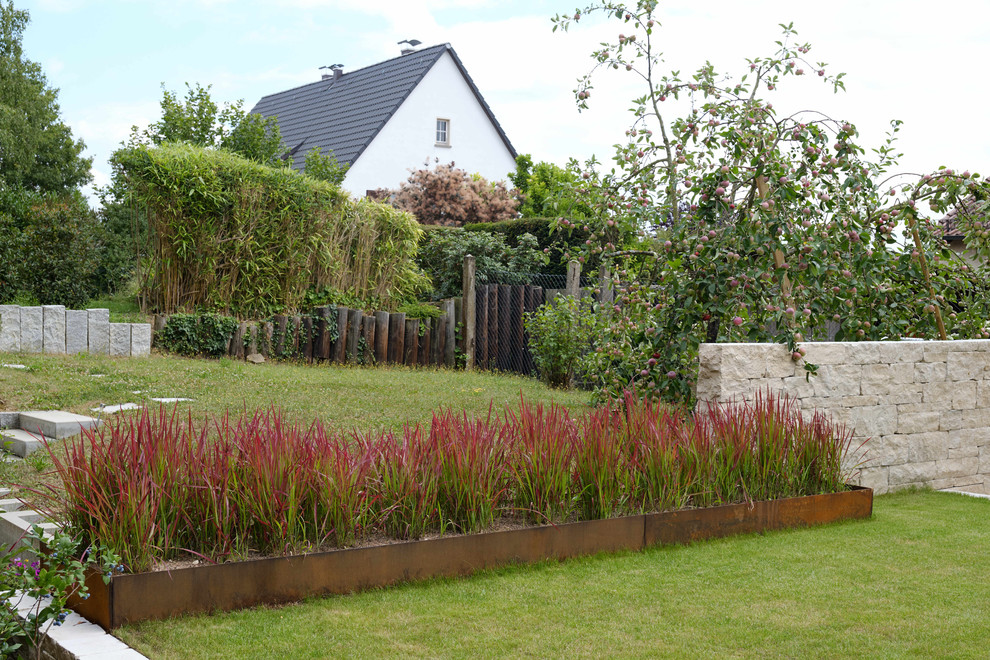 Ispirazione per un grande giardino xeriscape contemporaneo esposto a mezz'ombra dietro casa in estate con un muro di contenimento e pavimentazioni in pietra naturale