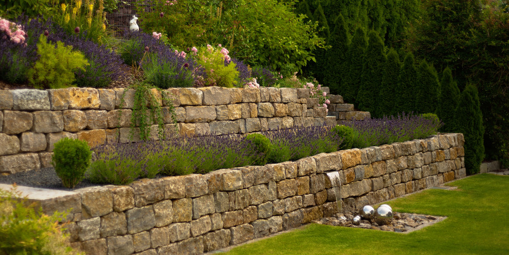 Inspiration för en stor vintage trädgård i delvis sol på sommaren, med en stödmur och naturstensplattor
