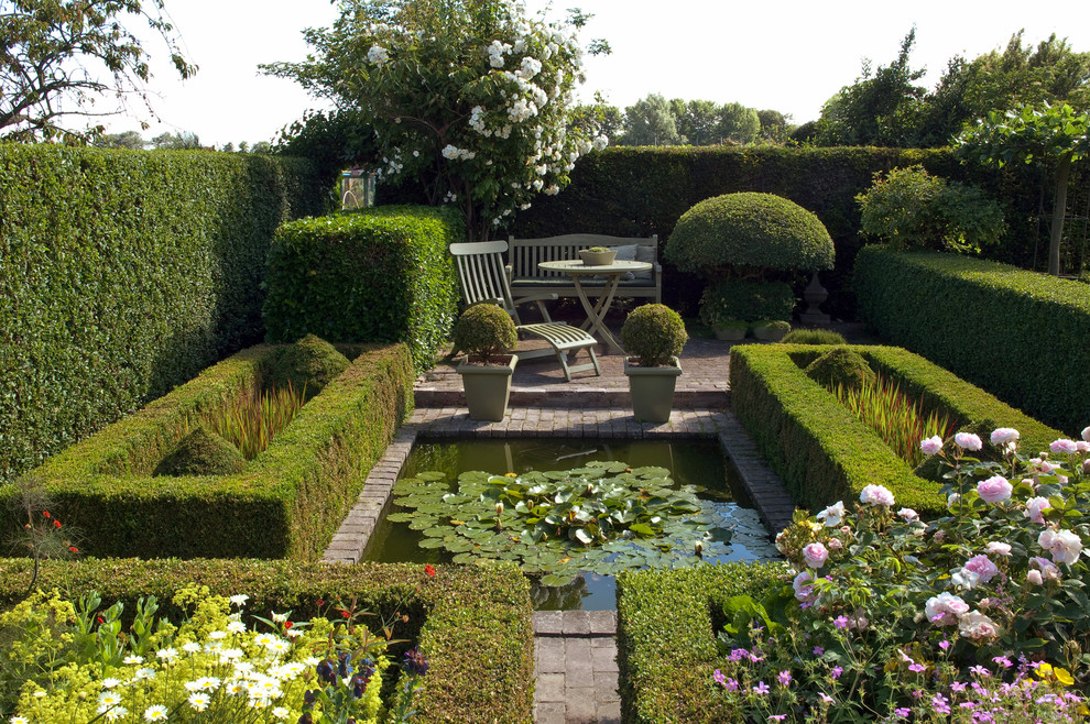 Idéer för en mellanstor klassisk formell trädgård i full sol, med en damm och marksten i tegel