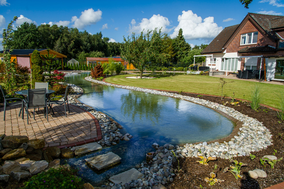 Immagine di un ampio giardino country esposto a mezz'ombra dietro casa in estate con pavimentazioni in pietra naturale e fontane