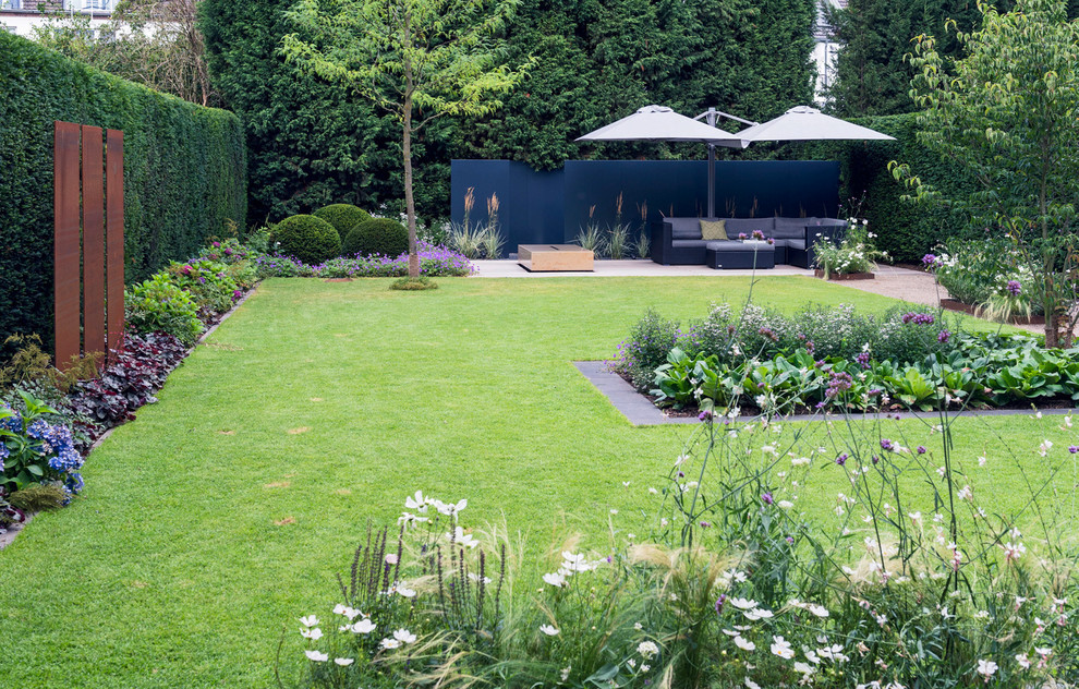 Modelo de jardín contemporáneo grande en verano en patio trasero con exposición parcial al sol y adoquines de hormigón