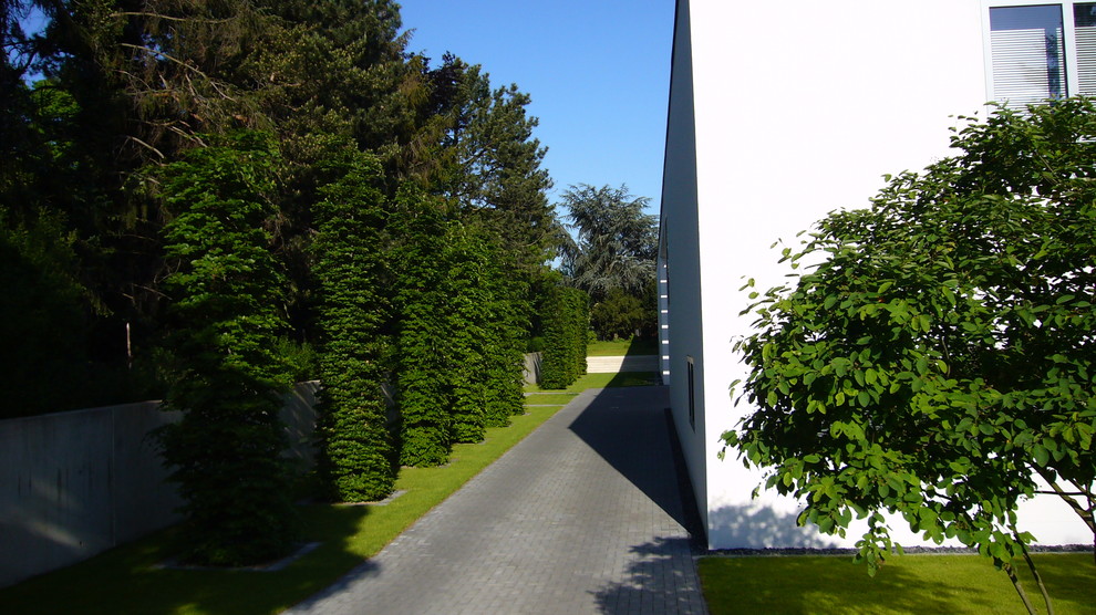 Großer Moderner Garten neben dem Haus mit Auffahrt und Natursteinplatten in Hamburg