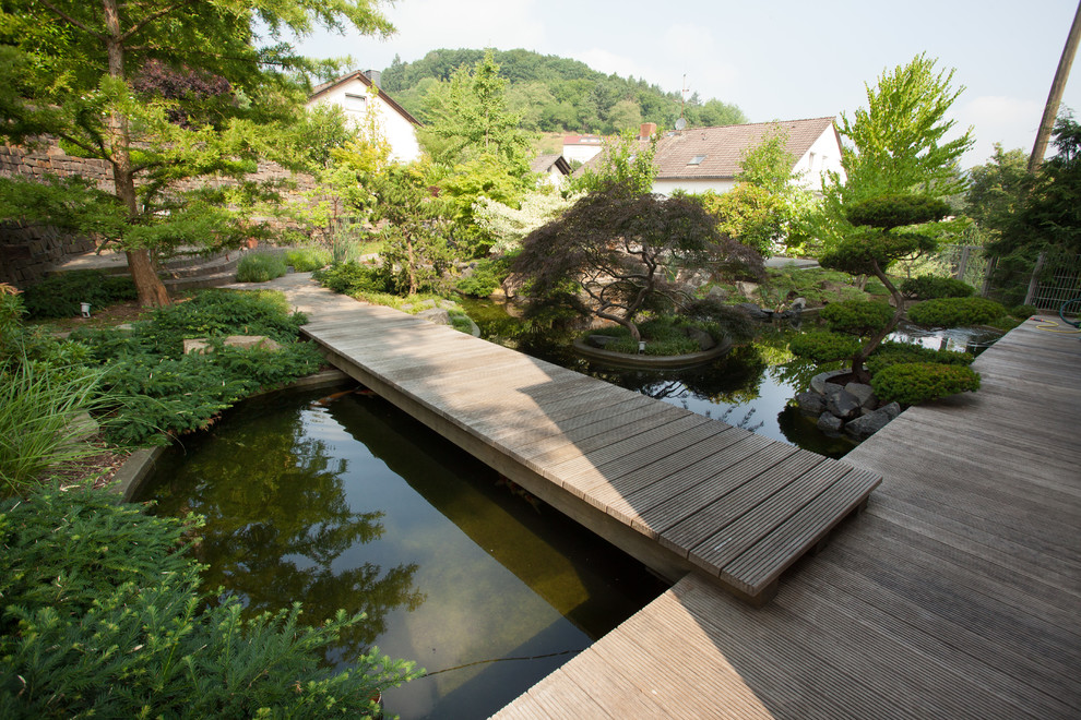 Exemple d'un grand jardin arrière asiatique l'automne avec une exposition partiellement ombragée, une terrasse en bois et un point d'eau.