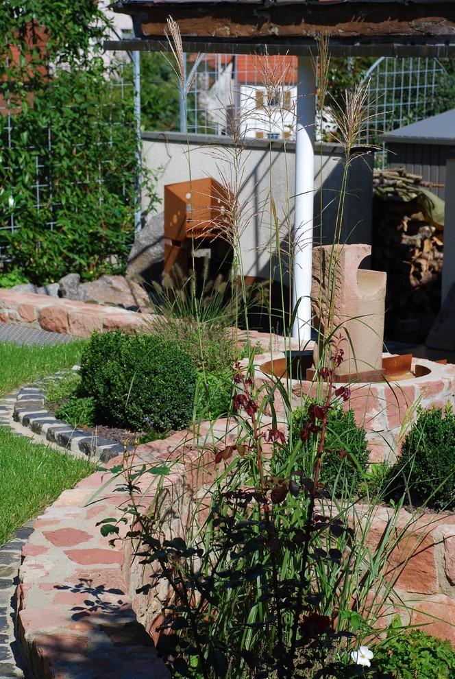 Foto di un giardino formale design esposto in pieno sole di medie dimensioni e dietro casa in estate con un muro di contenimento e pavimentazioni in pietra naturale