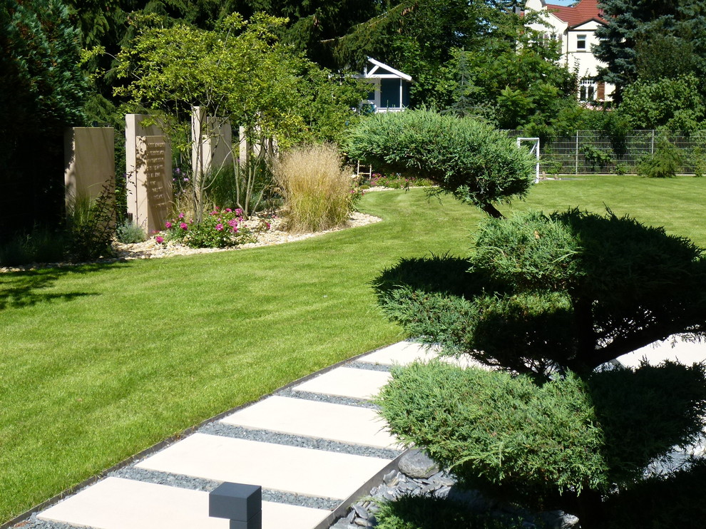 Mittelgroßer Garten im Sommer, neben dem Haus mit Sichtschutz, direkter Sonneneinstrahlung und Betonboden in Sonstige
