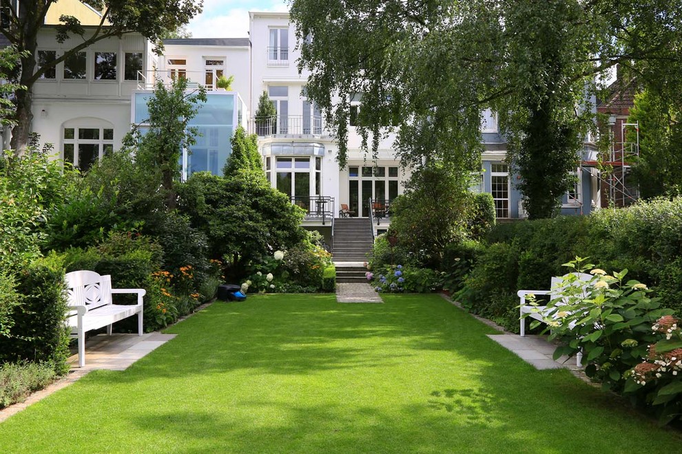 Modelo de jardín clásico grande en verano en patio trasero con jardín francés y exposición parcial al sol