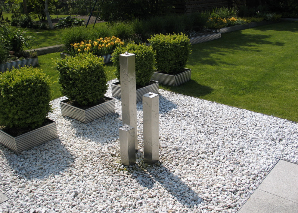 Exempel på en modern trädgård i full sol, med en fontän och grus