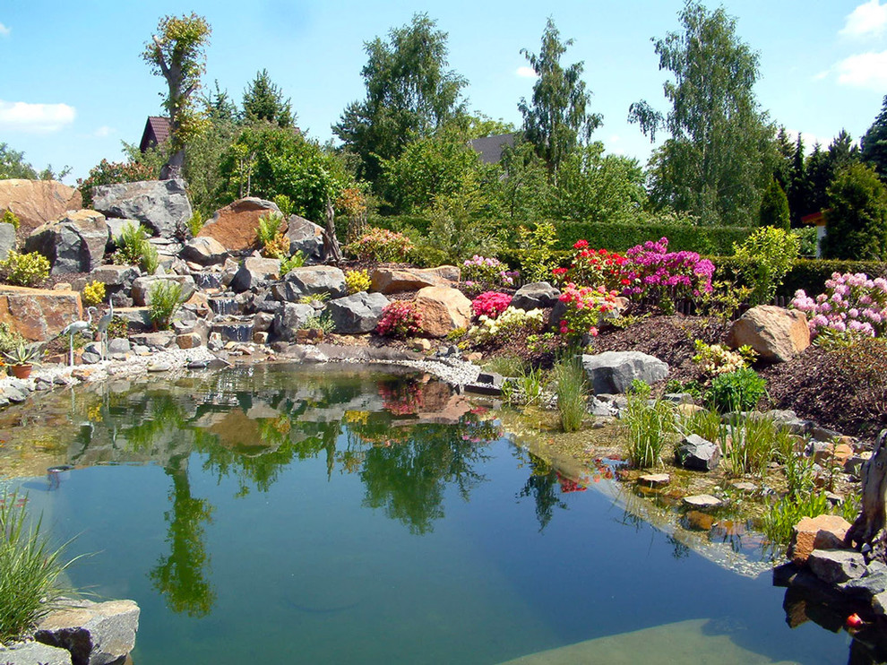Idée de décoration pour un grand jardin chalet l'été avec un point d'eau et une exposition ensoleillée.