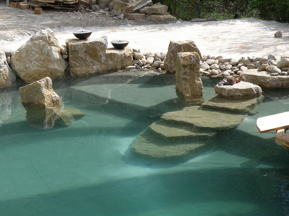 Foto de piscina tradicional de tamaño medio en patio lateral con adoquines de piedra natural