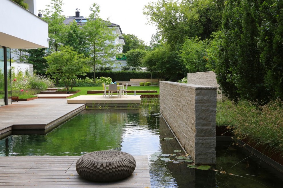 Exemple d'un très grand jardin à la française arrière tendance avec un point d'eau et une terrasse en bois.