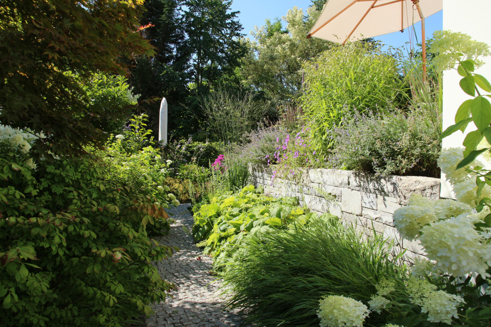 Ispirazione per un piccolo giardino chic esposto a mezz'ombra nel cortile laterale in primavera con un muro di contenimento e pavimentazioni in pietra naturale