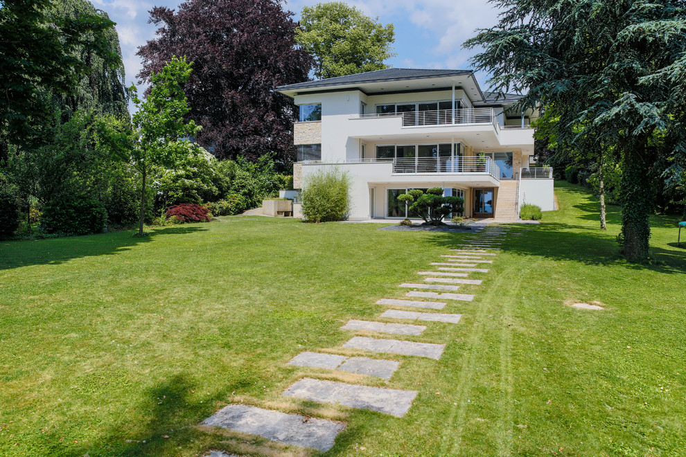 Moderner Gartenweg im Sommer mit direkter Sonneneinstrahlung und Natursteinplatten in Hannover
