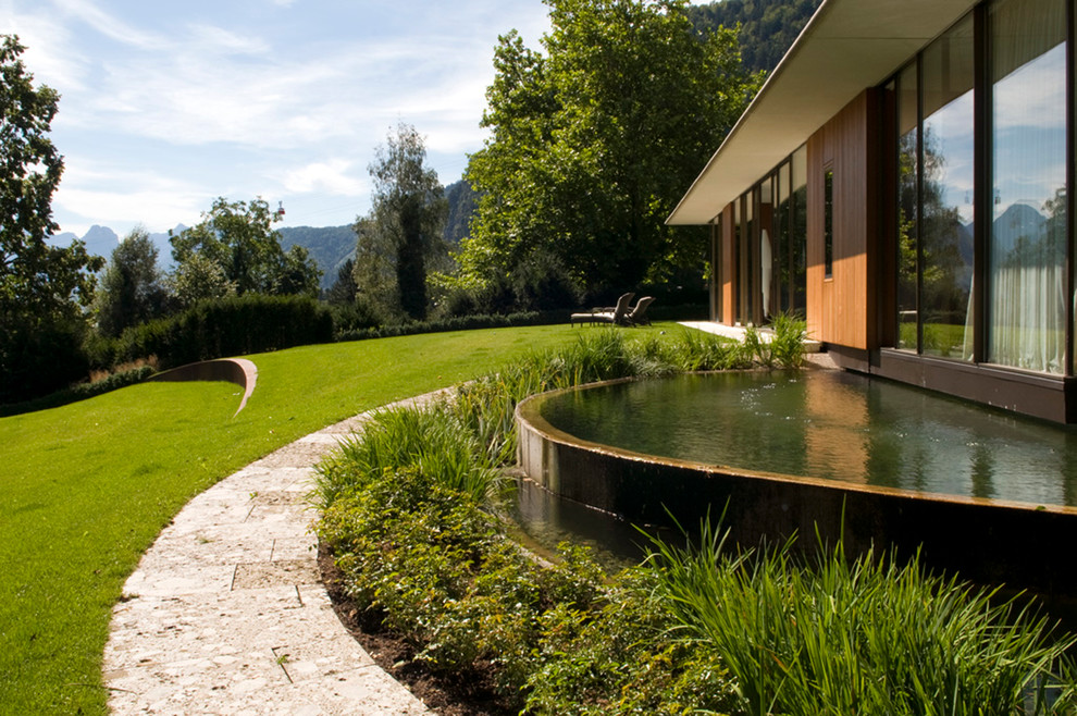 Immagine di un ampio giardino contemporaneo esposto in pieno sole con fontane, un pendio, una collina o una riva e pavimentazioni in pietra naturale