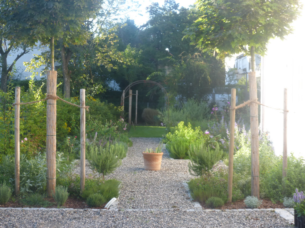 Foto de jardín campestre de tamaño medio en verano en patio lateral con jardín francés, parterre de flores, exposición total al sol y gravilla