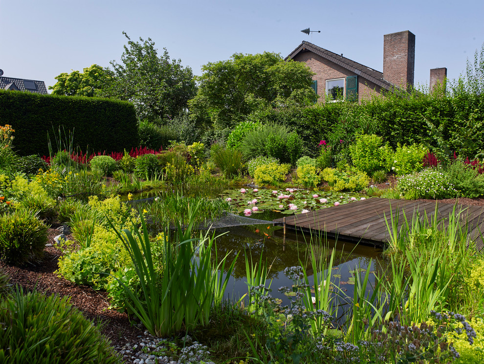 Foto de jardín tradicional grande en verano en patio trasero con exposición total al sol, entablado y fuente