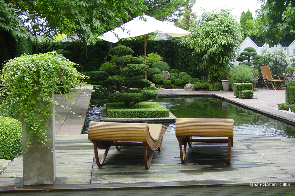 Imagen de jardín de secano de estilo zen de tamaño medio en verano en patio lateral con estanque, exposición parcial al sol y adoquines de piedra natural