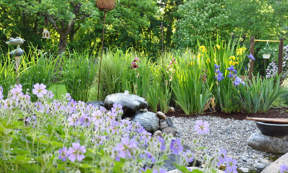 Foto di un grande laghetto da giardino country esposto a mezz'ombra in estate con un pendio, una collina o una riva e pavimentazioni in pietra naturale