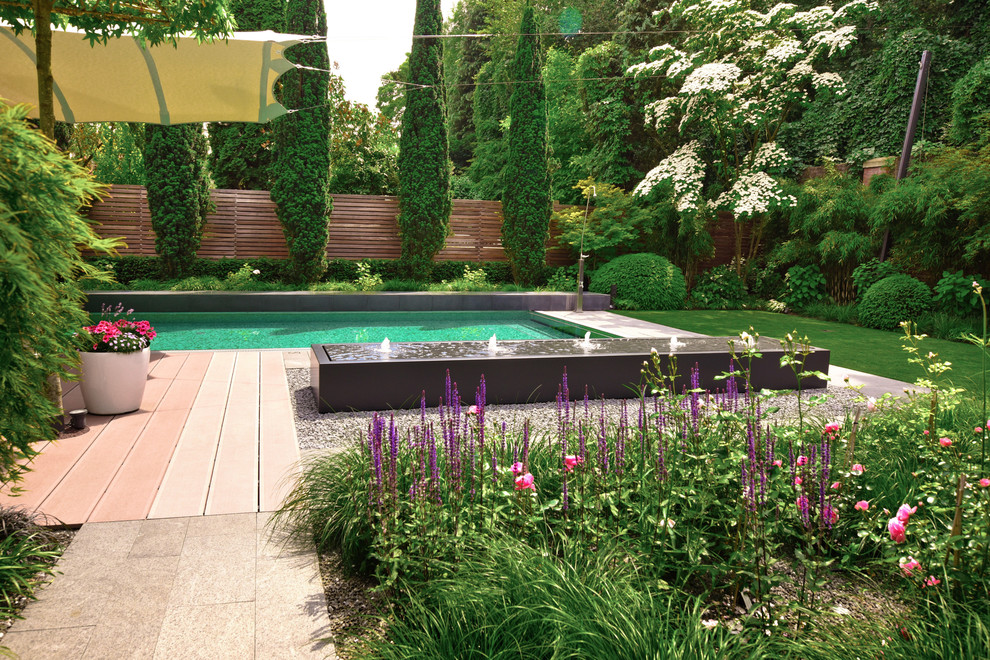 Imagen de jardín contemporáneo de tamaño medio en verano en patio trasero con fuente, exposición total al sol y entablado