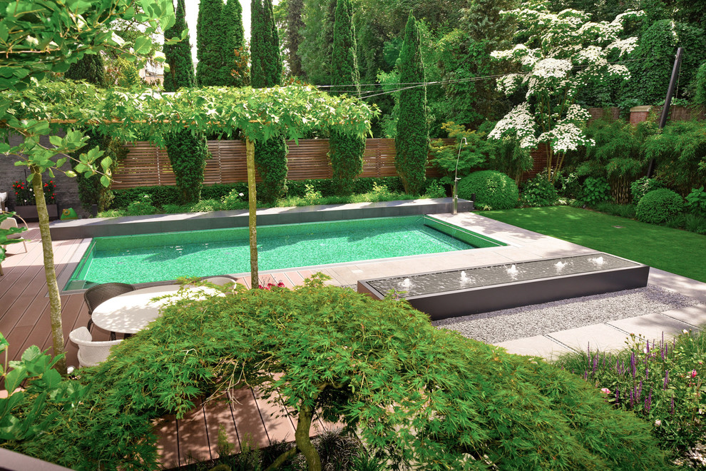 Modelo de jardín actual de tamaño medio en verano en patio trasero con fuente y exposición parcial al sol