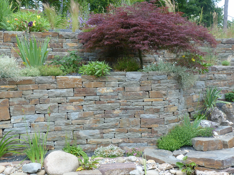 Inspiration pour un grand jardin rustique l'été avec un mur de soutènement, une exposition ensoleillée, une pente, une colline ou un talus et des pavés en pierre naturelle.