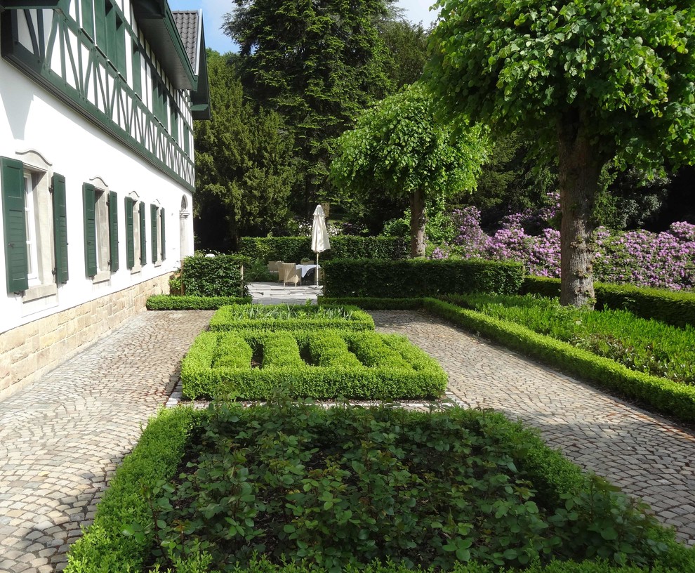 Imagen de jardín clásico grande con adoquines de piedra natural