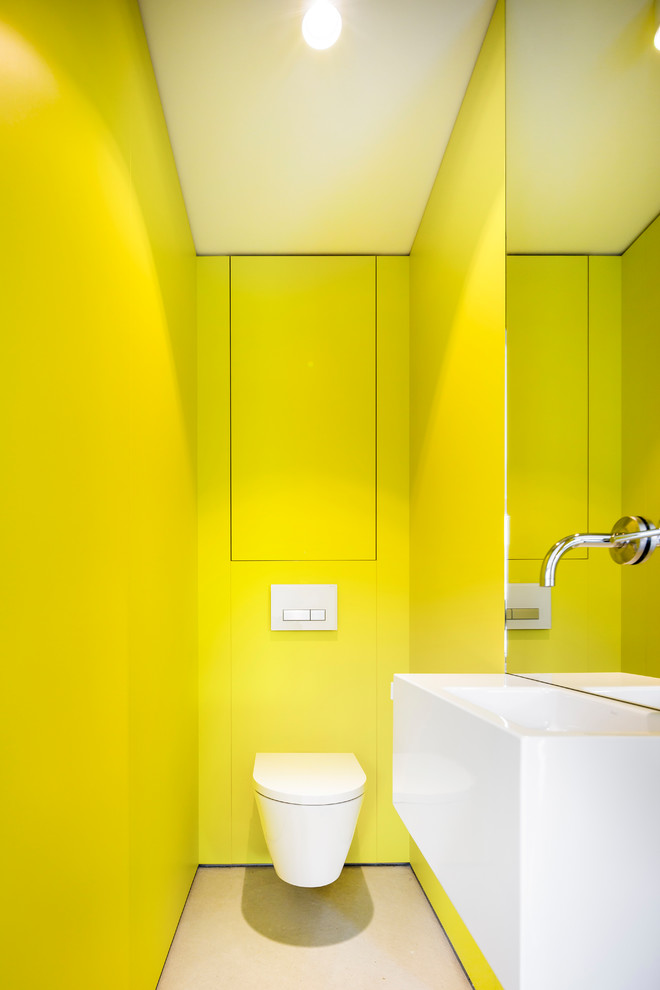 Kleine Moderne Gästetoilette mit flächenbündigen Schrankfronten, hellen Holzschränken, grüner Wandfarbe, Betonboden und grauem Boden in Stuttgart