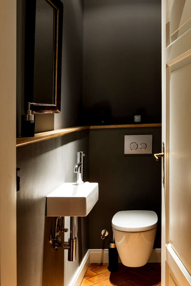 Idéer för att renovera ett mellanstort funkis toalett, med öppna hyllor, en vägghängd toalettstol, grå kakel, keramikplattor, grå väggar, mellanmörkt trägolv, ett konsol handfat, bänkskiva i akrylsten och brunt golv