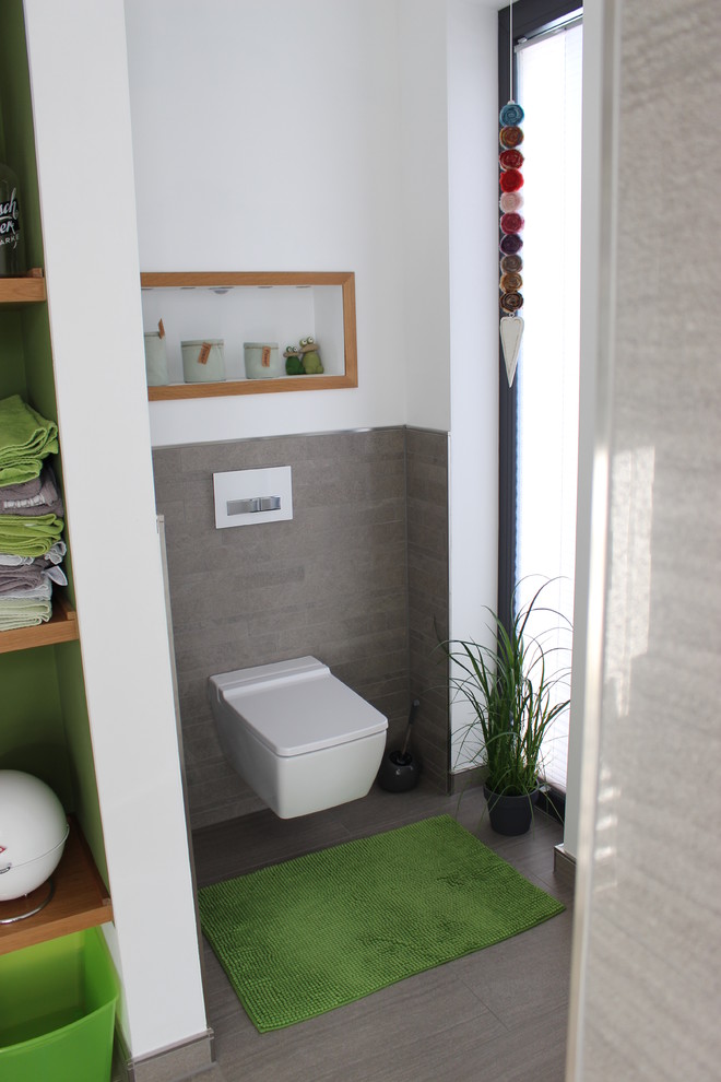Cette image montre un WC et toilettes design en bois brun de taille moyenne avec un placard sans porte, WC séparés, un carrelage gris, des carreaux de céramique, un mur blanc, un sol en carrelage de céramique et un lavabo posé.