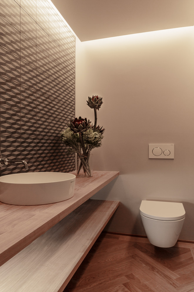 Cette image montre un petit WC suspendu minimaliste en bois clair avec un sol en bois brun, une vasque, un plan de toilette en bois et meuble-lavabo sur pied.