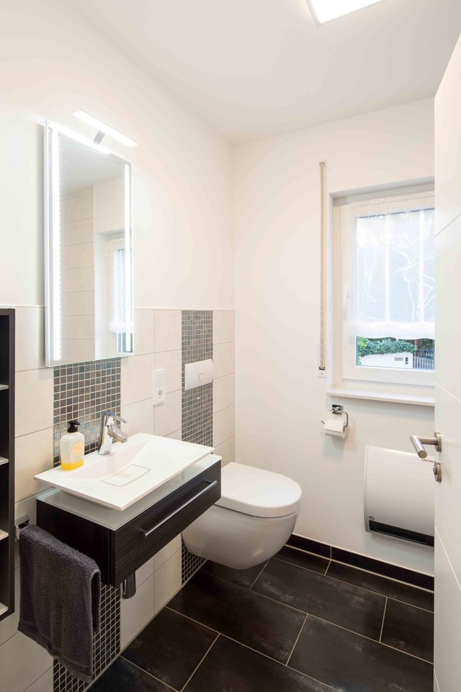 Gästetoilette mit grauen Fliesen, Mosaikfliesen, weißer Wandfarbe und schwarzem Boden in Sonstige
