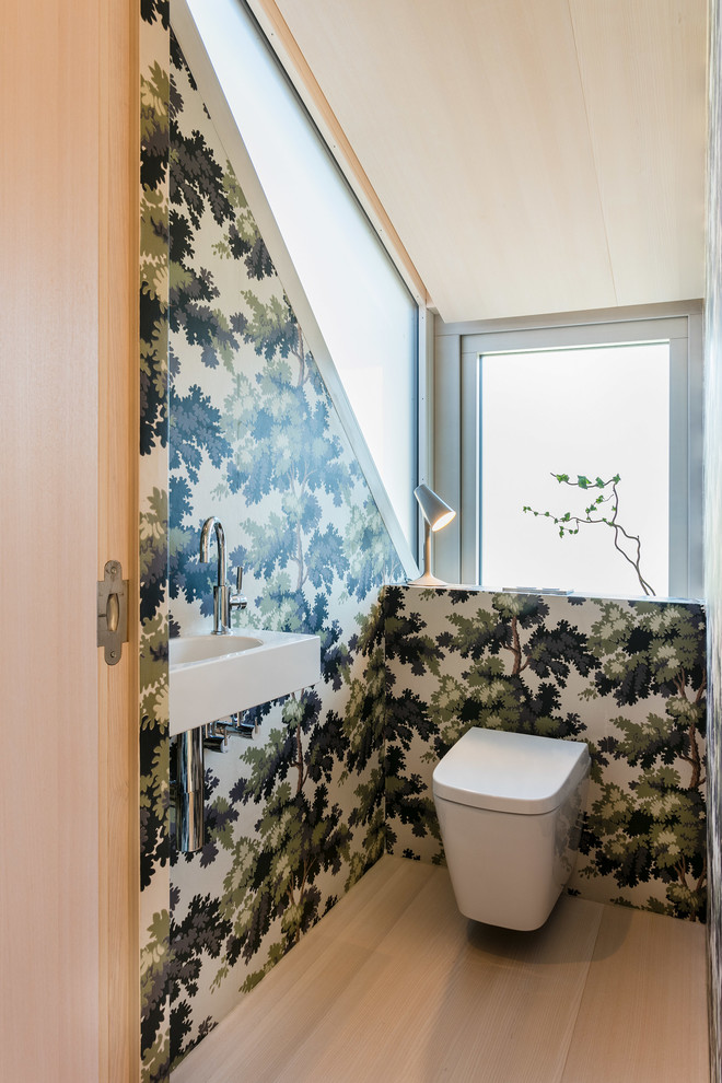 Kleine Moderne Gästetoilette mit Wandtoilette, bunten Wänden, braunem Holzboden, Wandwaschbecken und braunem Boden in Sonstige
