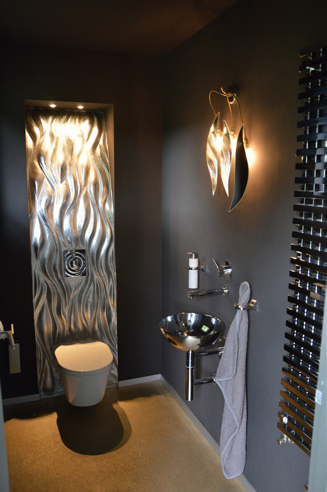 Exemple d'un WC et toilettes tendance avec un mur gris, WC à poser, carrelage en métal, sol en béton ciré, un lavabo posé et un sol beige.