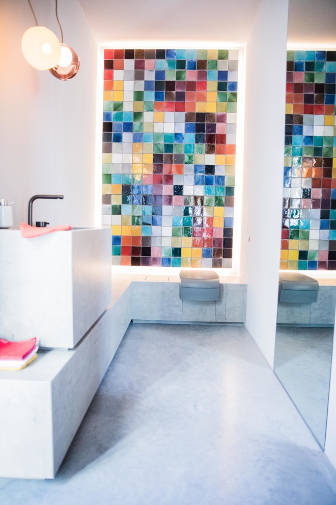 ミュンヘンにある中くらいなコンテンポラリースタイルのおしゃれなトイレ・洗面所 (コンクリートの床、マルチカラーのタイル、ガラスタイル、白い壁、ペデスタルシンク、コンクリートの洗面台、グレーの床、グレーの洗面カウンター) の写真