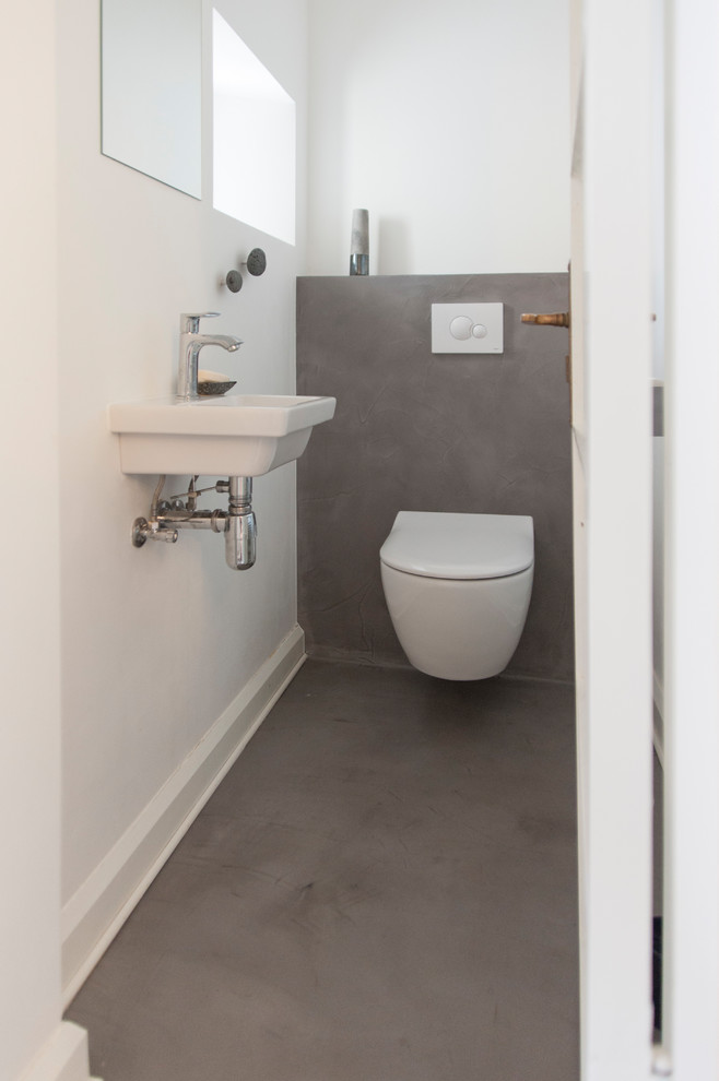 Kleine Moderne Gästetoilette mit Wandtoilette mit Spülkasten, weißer Wandfarbe, Betonboden und grauem Boden in Berlin