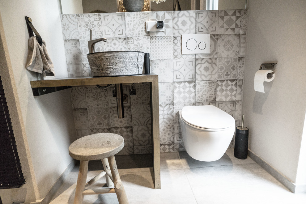 Пример оригинального дизайна: маленький туалет в стиле лофт с серой плиткой, цементной плиткой, бежевыми стенами, бетонным полом, настольной раковиной, серым полом и черной столешницей для на участке и в саду