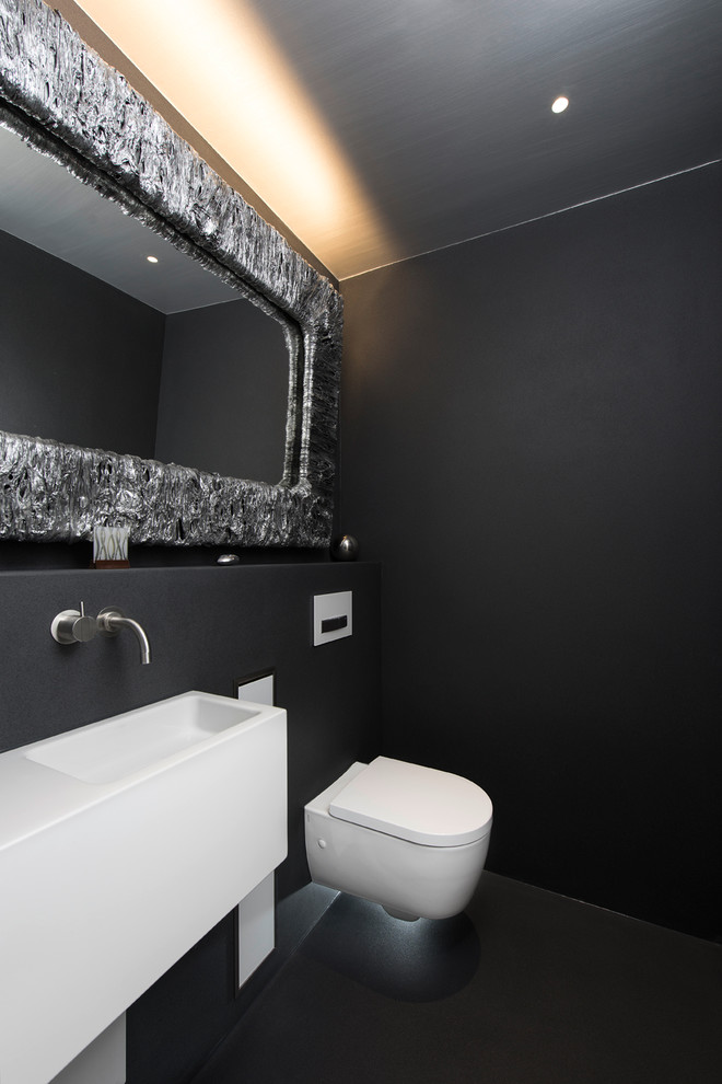 Idéer för ett mellanstort industriellt toalett, med ett väggmonterat handfat, svarta väggar och en vägghängd toalettstol