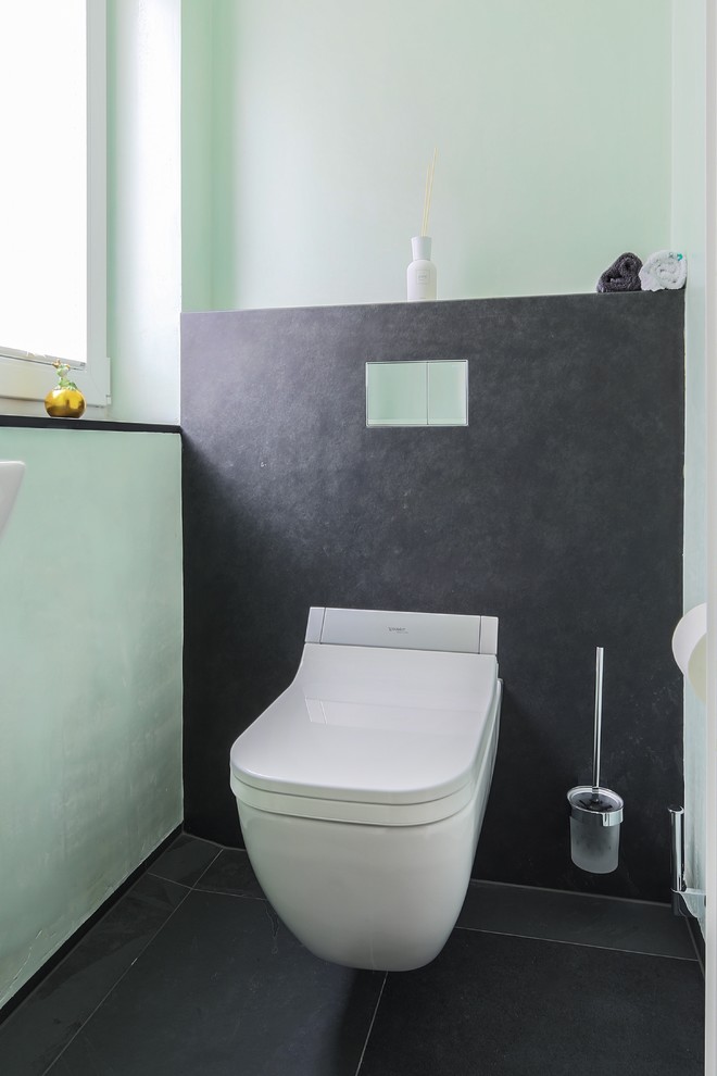 This is an example of a small contemporary cloakroom in Frankfurt with a wall mounted toilet, grey tiles and stone slabs.