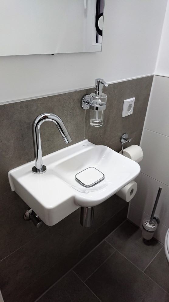 Inspiration för ett litet funkis toalett, med en vägghängd toalettstol, vit kakel, keramikplattor, vita väggar, klinkergolv i porslin, ett väggmonterat handfat och grått golv