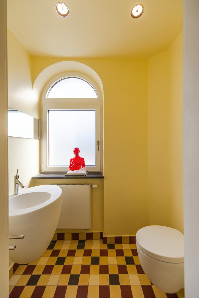 Mittelgroße Moderne Gästetoilette mit Wandtoilette, Keramikfliesen, gelber Wandfarbe und Wandwaschbecken in Köln