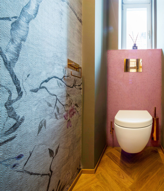 Modelo de aseo asiático pequeño con sanitario de pared, baldosas y/o azulejos grises, baldosas y/o azulejos rosa, baldosas y/o azulejos en mosaico, paredes multicolor y suelo de madera en tonos medios