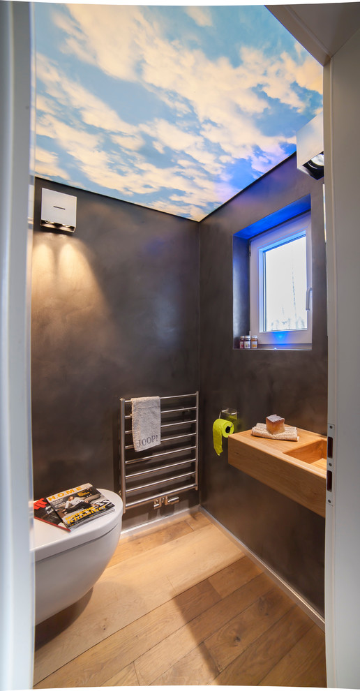 Immagine di un bagno di servizio design con pareti nere, pavimento in legno massello medio, lavabo sospeso e pavimento marrone