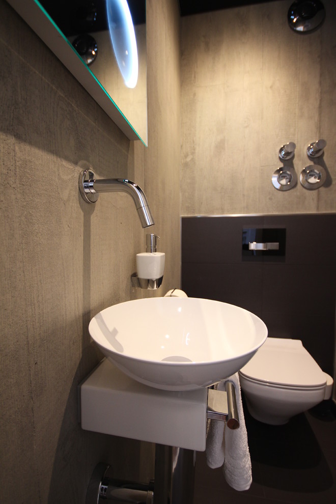 Kleine Moderne Gästetoilette mit Wandtoilette, grauen Fliesen, Keramikfliesen, grauer Wandfarbe, Keramikboden und Aufsatzwaschbecken in Köln