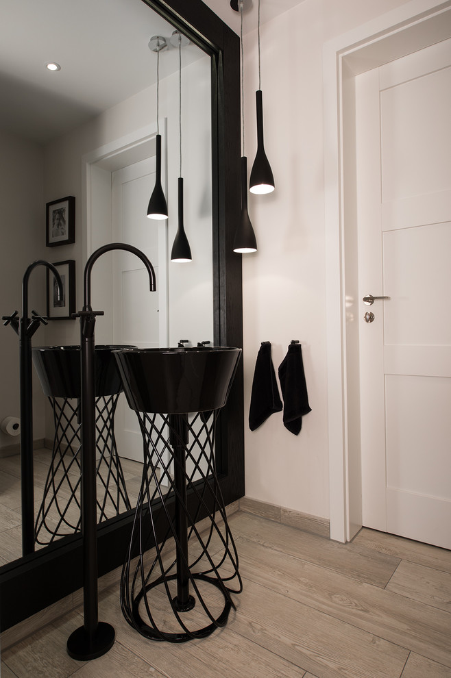 This is an example of a medium sized contemporary cloakroom in Dortmund with white walls, a pedestal sink and light hardwood flooring.