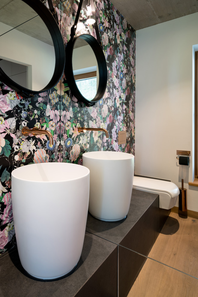 Esempio di un piccolo bagno di servizio contemporaneo con WC sospeso, pareti multicolore, pavimento in legno massello medio, lavabo a colonna, pavimento marrone e top marrone