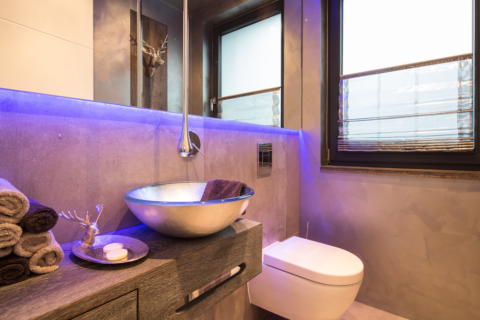 Immagine di un piccolo bagno di servizio minimal con ante in legno scuro, WC sospeso, piastrelle beige, lavabo a bacinella, top in legno e top marrone