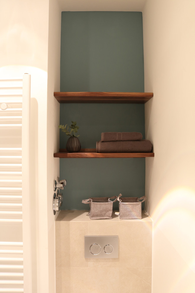 Modern inredning av ett litet toalett, med en vägghängd toalettstol, blå väggar och beiget golv