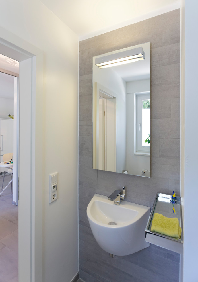Foto di un bagno di servizio minimal con WC sospeso, piastrelle grigie, piastrelle in ceramica, pareti bianche, pavimento con piastrelle in ceramica, lavabo sospeso e pavimento grigio