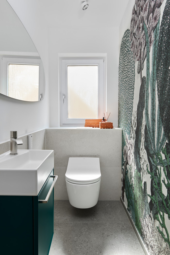 Exemple d'un petit WC suspendu tendance avec un placard à porte plane, des portes de placards vertess, un carrelage gris, un mur blanc et un sol gris.