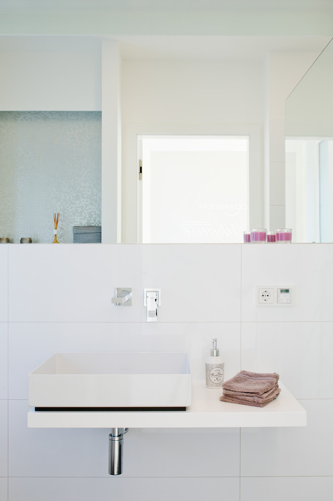 Свежая идея для дизайна: туалет среднего размера в современном стиле с белой плиткой, белыми стенами, настольной раковиной и керамической плиткой - отличное фото интерьера